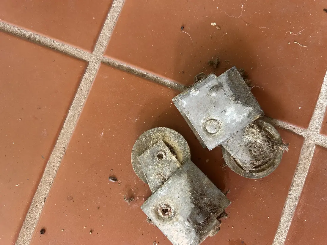 Old worn sliding door rollers removed from an off-track patio door